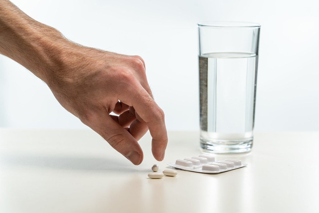 Hand picking up a tablet beside a glass of water
