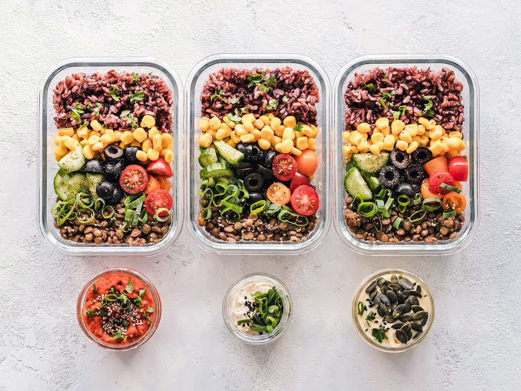 Glass meal prep containers filled with grains, beans and vegetables