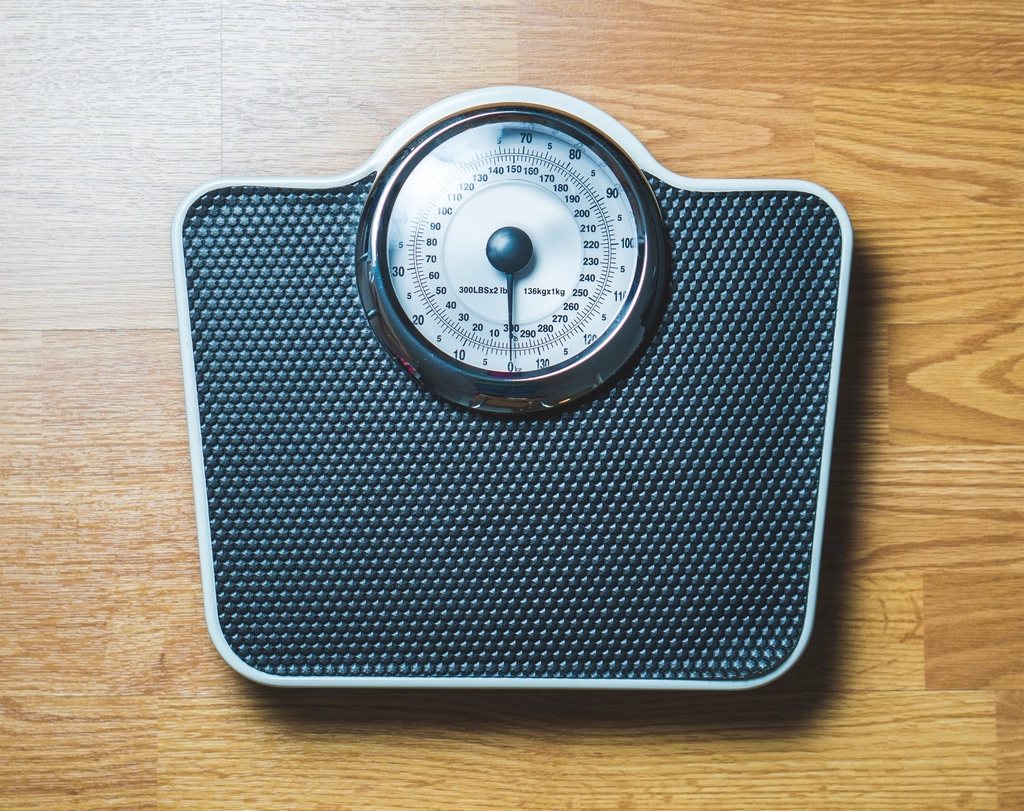 Analogue bathroom weight scale on a tiled floor