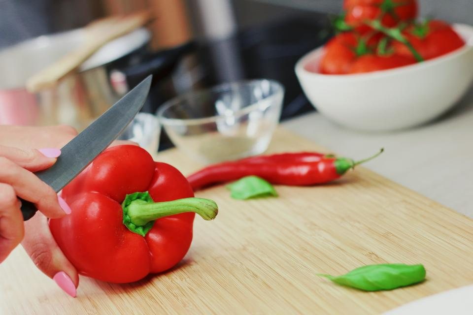 Knife slicing red peppers on a cutting board