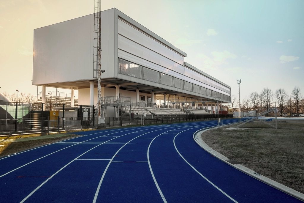 Blue running track curving past a stadium