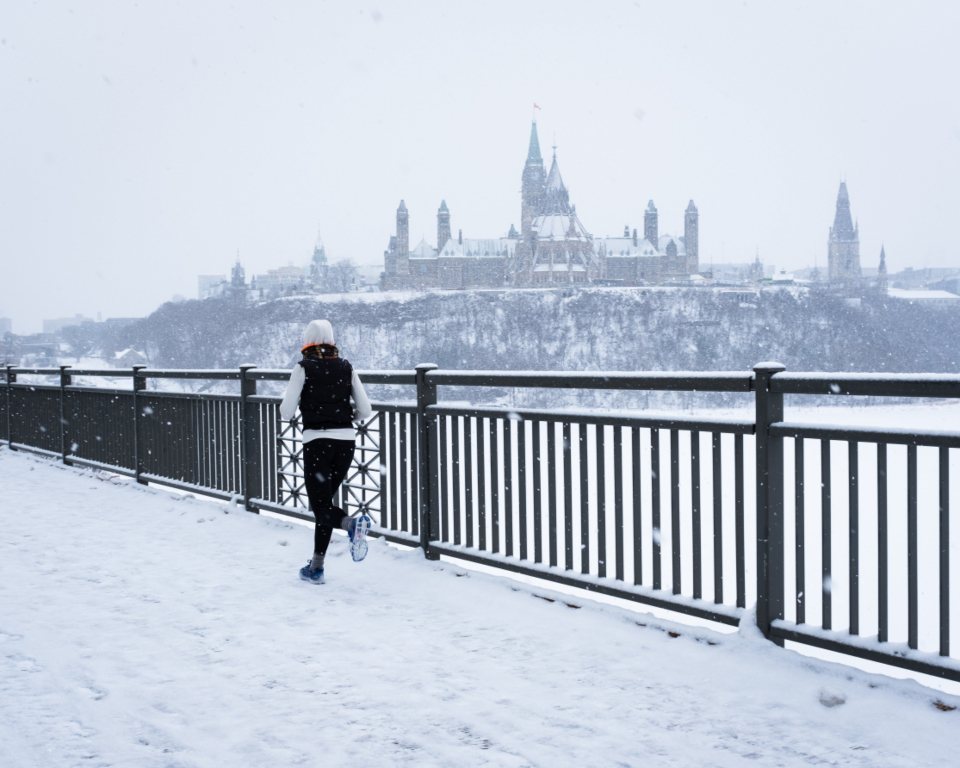 Runner on a snowy path below Parliament Hill in Ottawa